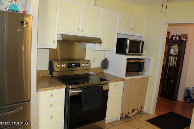kitchen featuring appliances with stainless steel finishes, light tile patterned floors, and under cabinet range hood