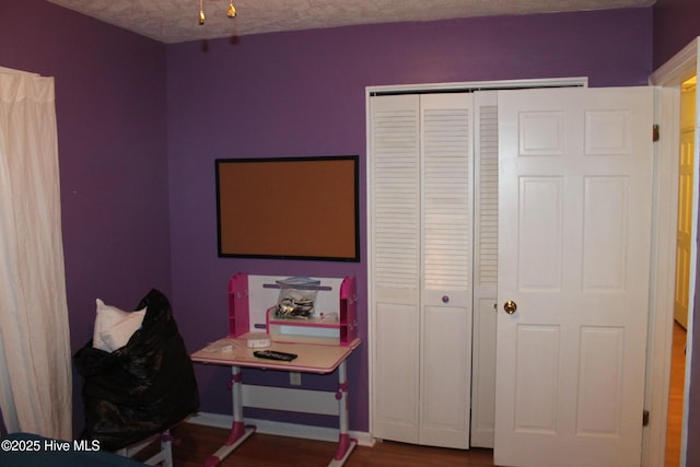 recreation room with a textured ceiling, baseboards, and wood finished floors