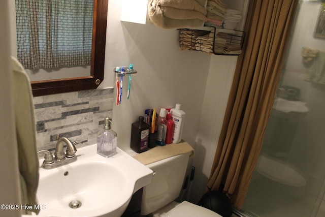 bathroom with toilet, a stall shower, decorative backsplash, and a sink