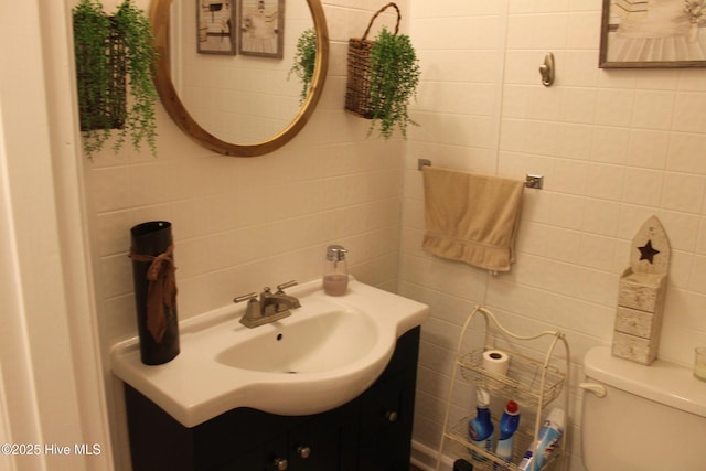 half bathroom with tasteful backsplash, vanity, tile walls, and toilet
