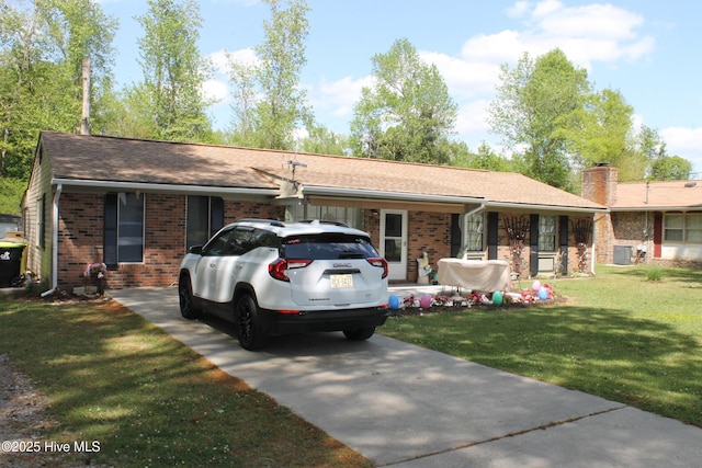 single story home with concrete driveway, a chimney, a front yard, brick siding, and central AC unit