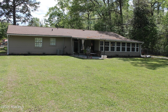 rear view of property with cooling unit, a sunroom, a patio area, and a lawn