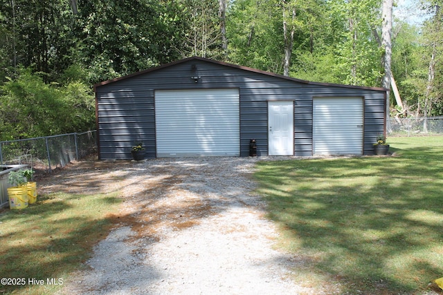 detached garage featuring a forest view and fence