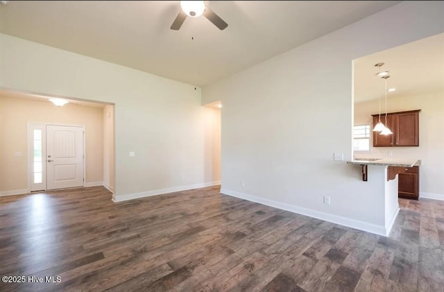 unfurnished living room with baseboards, a ceiling fan, and dark wood finished floors
