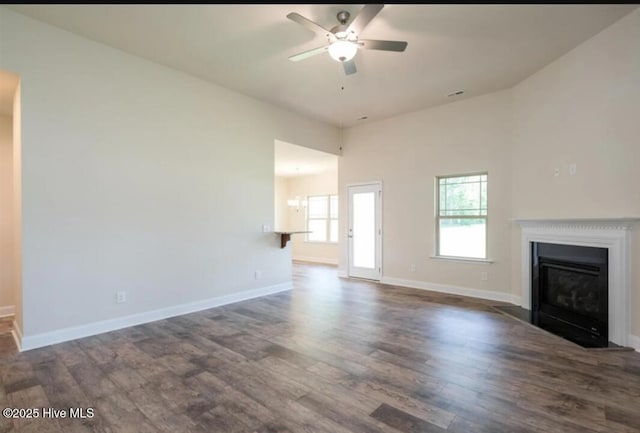 unfurnished living room with a fireplace with flush hearth, wood finished floors, ceiling fan, and baseboards