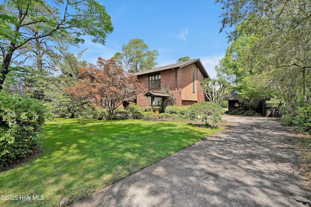view of front of house featuring a front lawn, driveway, and brick siding