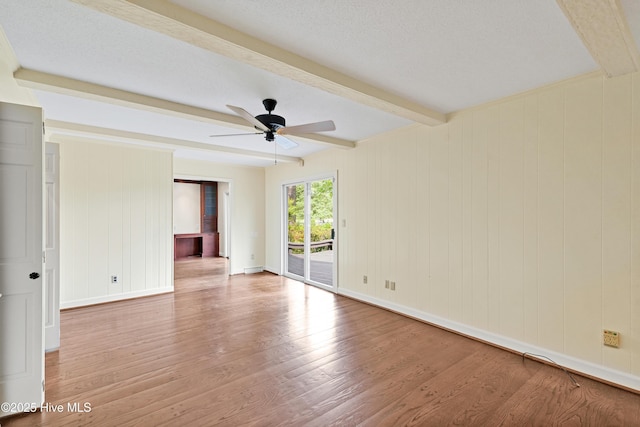 spare room featuring beamed ceiling, a ceiling fan, wood finished floors, and baseboards