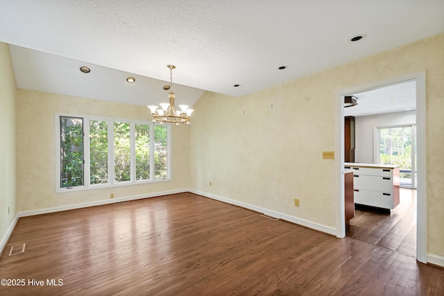 empty room with dark wood-style flooring, baseboards, visible vents, a notable chandelier, and lofted ceiling