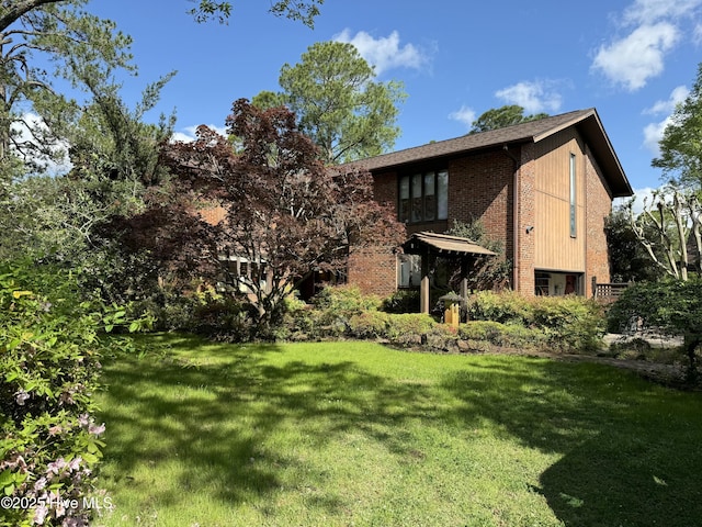 rear view of property with a yard and brick siding