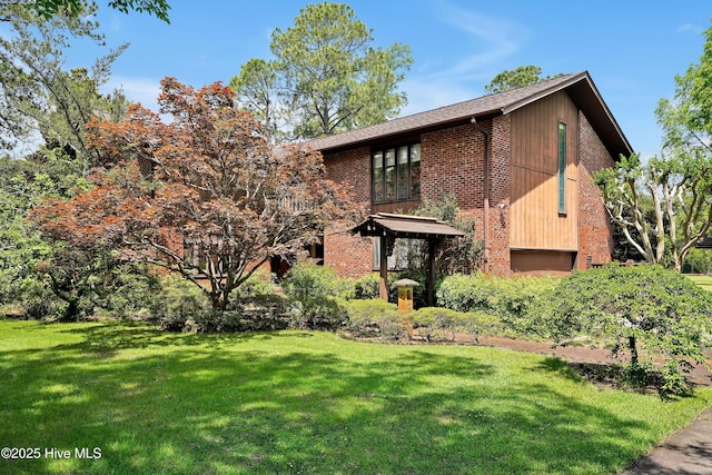 view of front of home featuring a front lawn, an attached garage, and brick siding