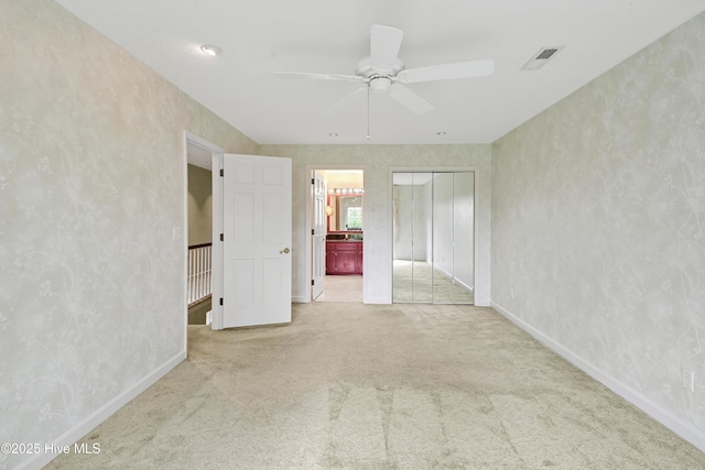 unfurnished bedroom with connected bathroom, a closet, visible vents, carpet, and baseboards