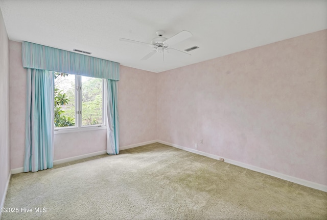 empty room with visible vents, a ceiling fan, and carpet flooring