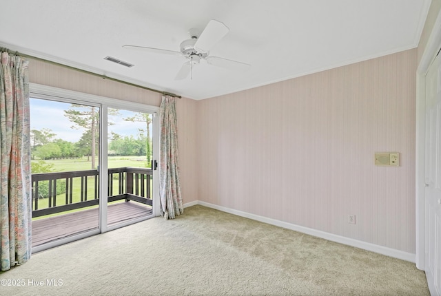 carpeted spare room with baseboards, visible vents, ornamental molding, and a ceiling fan