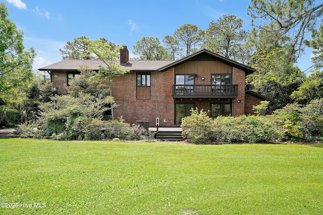 rear view of house featuring a lawn, a wooden deck, brick siding, and a chimney