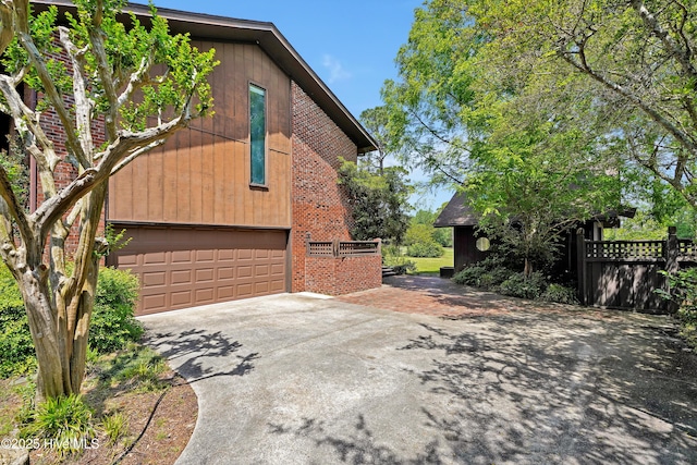 view of home's exterior featuring fence, concrete driveway, brick siding, and a garage