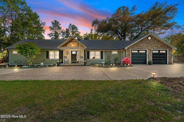 view of front of property with an attached garage, roof with shingles, a yard, and concrete driveway