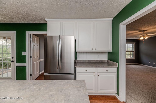 kitchen featuring a textured ceiling, freestanding refrigerator, ceiling fan, and white cabinets
