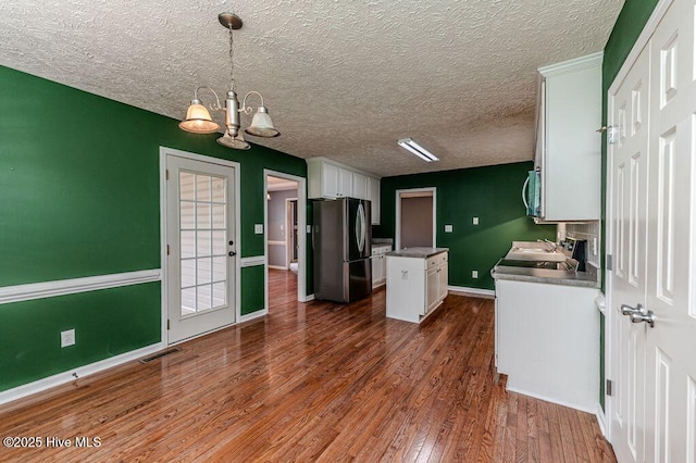 kitchen featuring visible vents, white cabinets, a center island, freestanding refrigerator, and dark wood finished floors