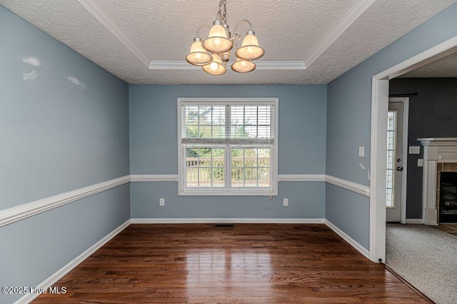 unfurnished room featuring a tile fireplace, a chandelier, wood finished floors, and a textured ceiling