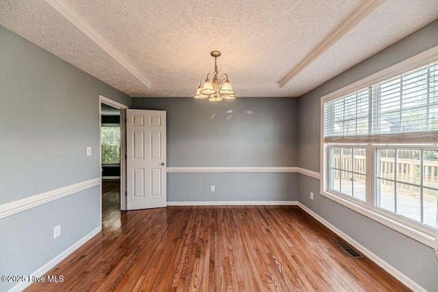 spare room featuring a notable chandelier, visible vents, a textured ceiling, and hardwood / wood-style floors