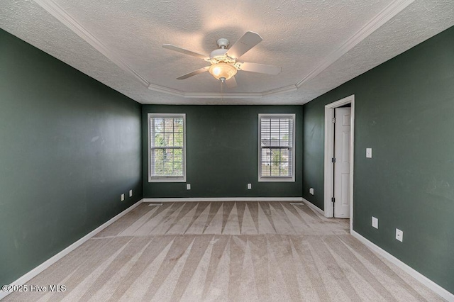 empty room with baseboards, a textured ceiling, carpet floors, a tray ceiling, and ceiling fan