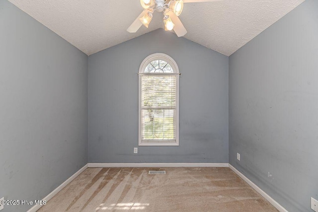 carpeted spare room featuring visible vents, baseboards, a ceiling fan, a textured ceiling, and lofted ceiling