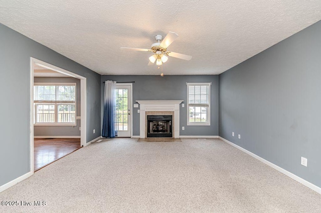 unfurnished living room with ceiling fan, baseboards, carpet, and a wealth of natural light