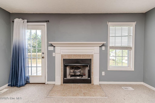 unfurnished living room with a tile fireplace, visible vents, baseboards, and carpet