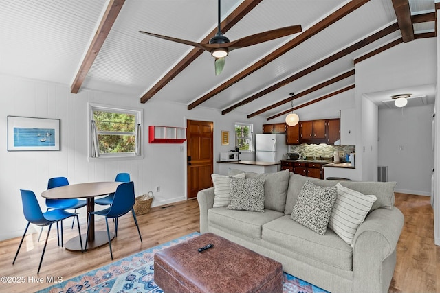 living area featuring vaulted ceiling with beams, a wealth of natural light, and light wood-style flooring