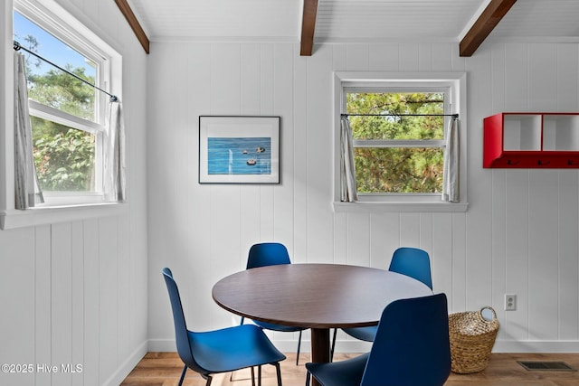 dining room with beam ceiling, wood finished floors, and a healthy amount of sunlight