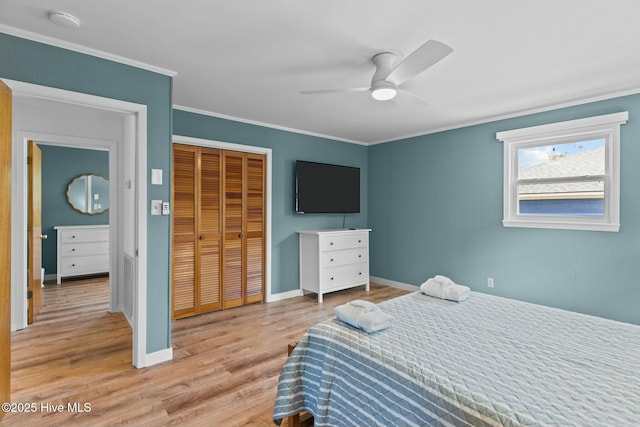 bedroom with light wood-style floors, baseboards, ornamental molding, and a closet