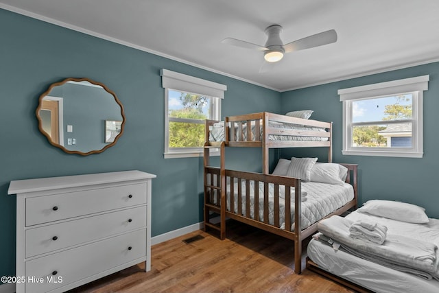 bedroom featuring crown molding, multiple windows, light wood-style flooring, and visible vents