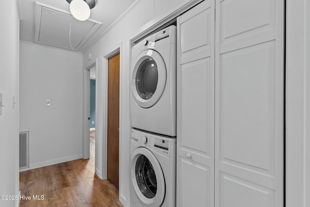 washroom featuring attic access, laundry area, visible vents, stacked washer / dryer, and wood finished floors