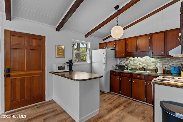kitchen featuring dark countertops, lofted ceiling with beams, white appliances, and a sink