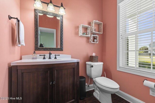 bathroom with toilet, wood finished floors, vanity, and baseboards
