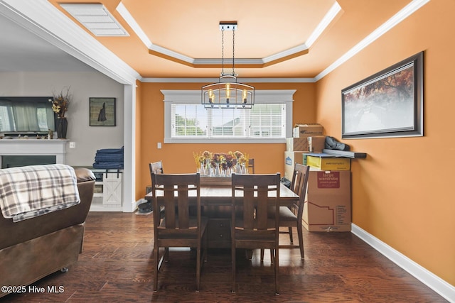 dining area with crown molding, wood finished floors, a raised ceiling, a notable chandelier, and baseboards