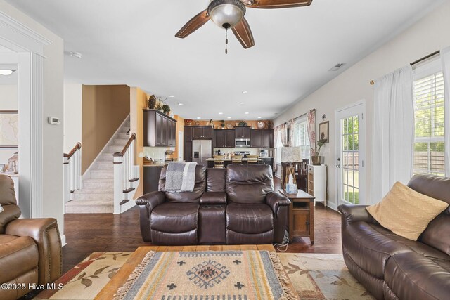 living area featuring stairway, visible vents, a ceiling fan, and light wood finished floors