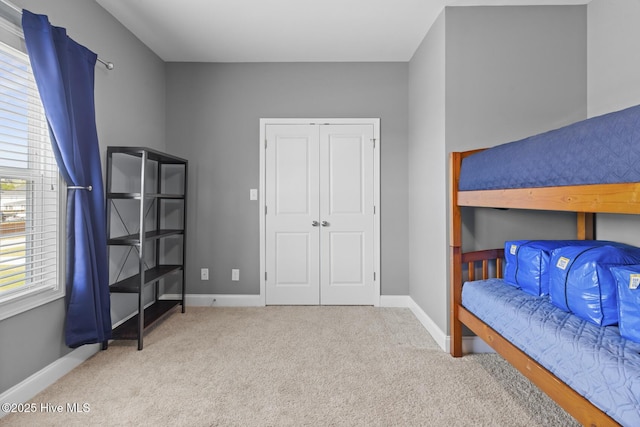 carpeted bedroom with a closet and baseboards