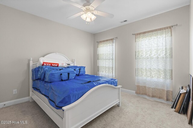 carpeted bedroom with visible vents, baseboards, and a ceiling fan