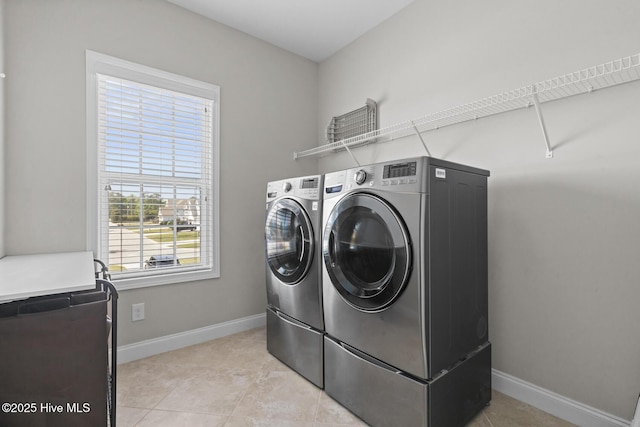 washroom with washer and clothes dryer, light tile patterned floors, laundry area, and baseboards