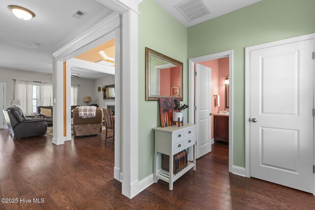 hallway featuring baseboards, dark wood finished floors, and visible vents