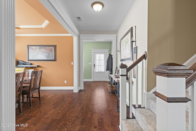 foyer entrance with visible vents, baseboards, crown molding, stairway, and wood finished floors