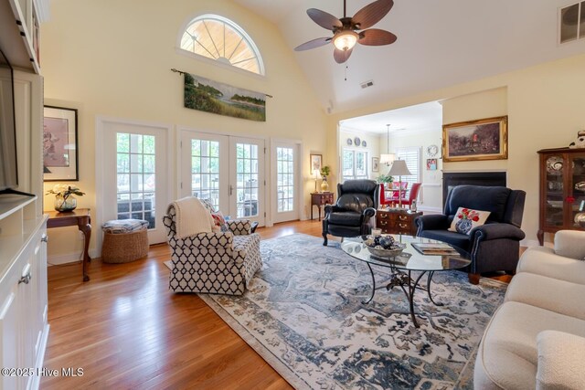 living area featuring light wood-style floors, ceiling fan, a fireplace, and visible vents