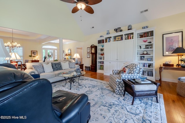 living room featuring visible vents, baseboards, wood finished floors, and ceiling fan with notable chandelier