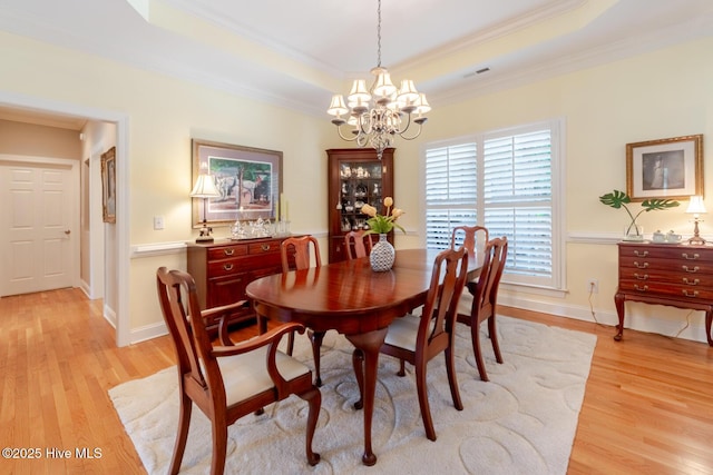 dining room with light wood finished floors, crown molding, an inviting chandelier, and visible vents