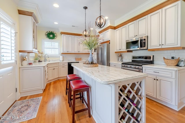 kitchen featuring a kitchen breakfast bar, ornamental molding, a chandelier, a kitchen island, and stainless steel appliances