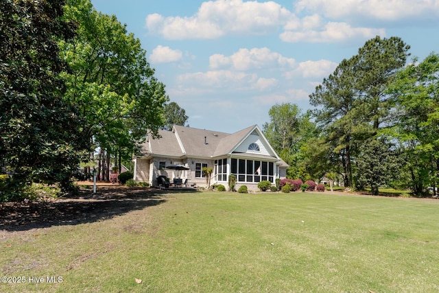 rear view of house with a sunroom and a lawn