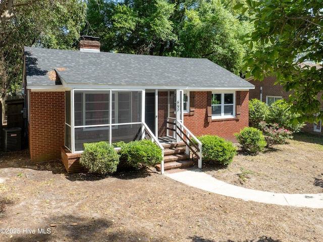 907 Bonham Ave, Wilmington, NC 28403 - view of front of house with a chimney, brick siding, cooling unit, and a shingled roof
