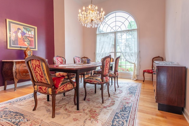 dining room featuring light wood-style flooring, an inviting chandelier, and baseboards