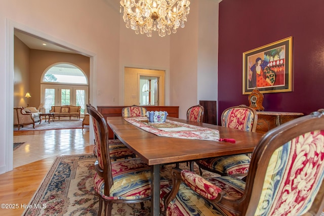 dining area featuring a towering ceiling, an inviting chandelier, and wood finished floors